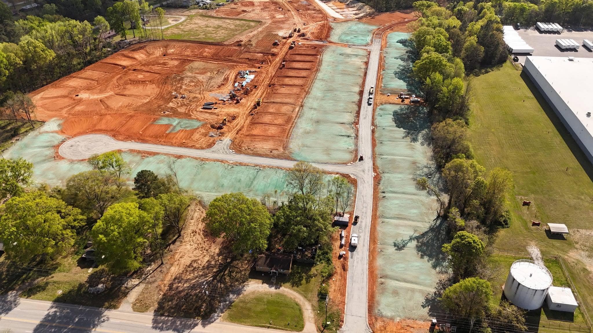 Aerial view of a graded residential subdivision with hydroseeded lots and a stormwater retention area under construction near Indian Trail, NC