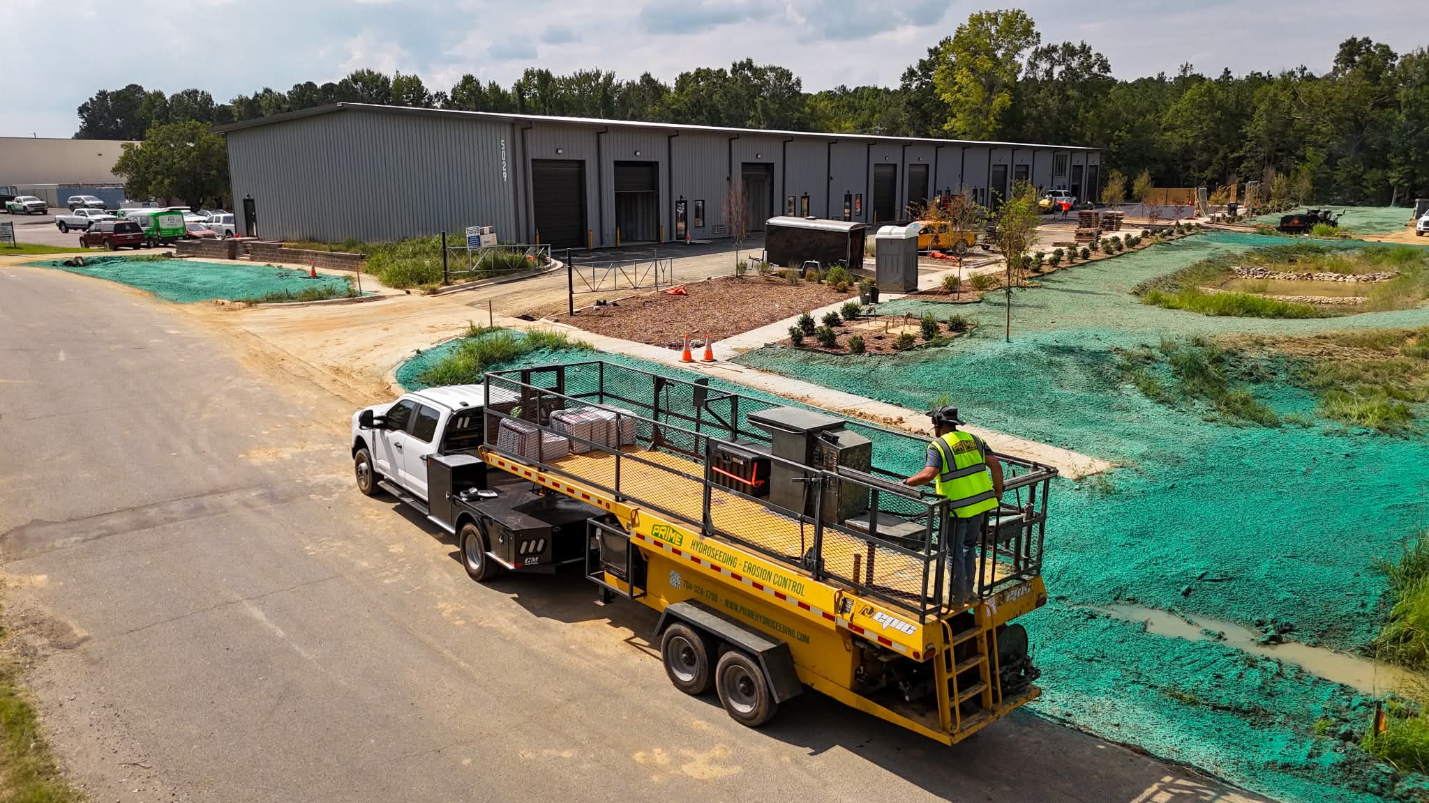 Aerial view of a Prime Hydroseeding truck and crew applying hydroseed at a new commercial warehouse development
