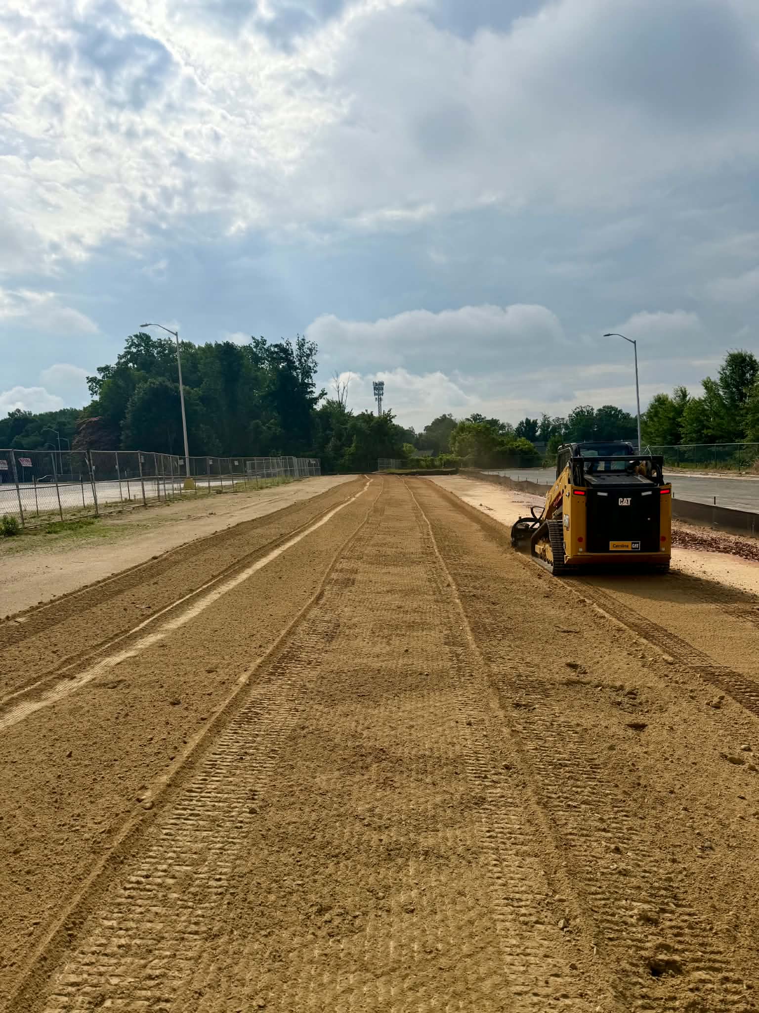 Graded and prepped commercial site ready for hydroseeding, with soil preparation equipment