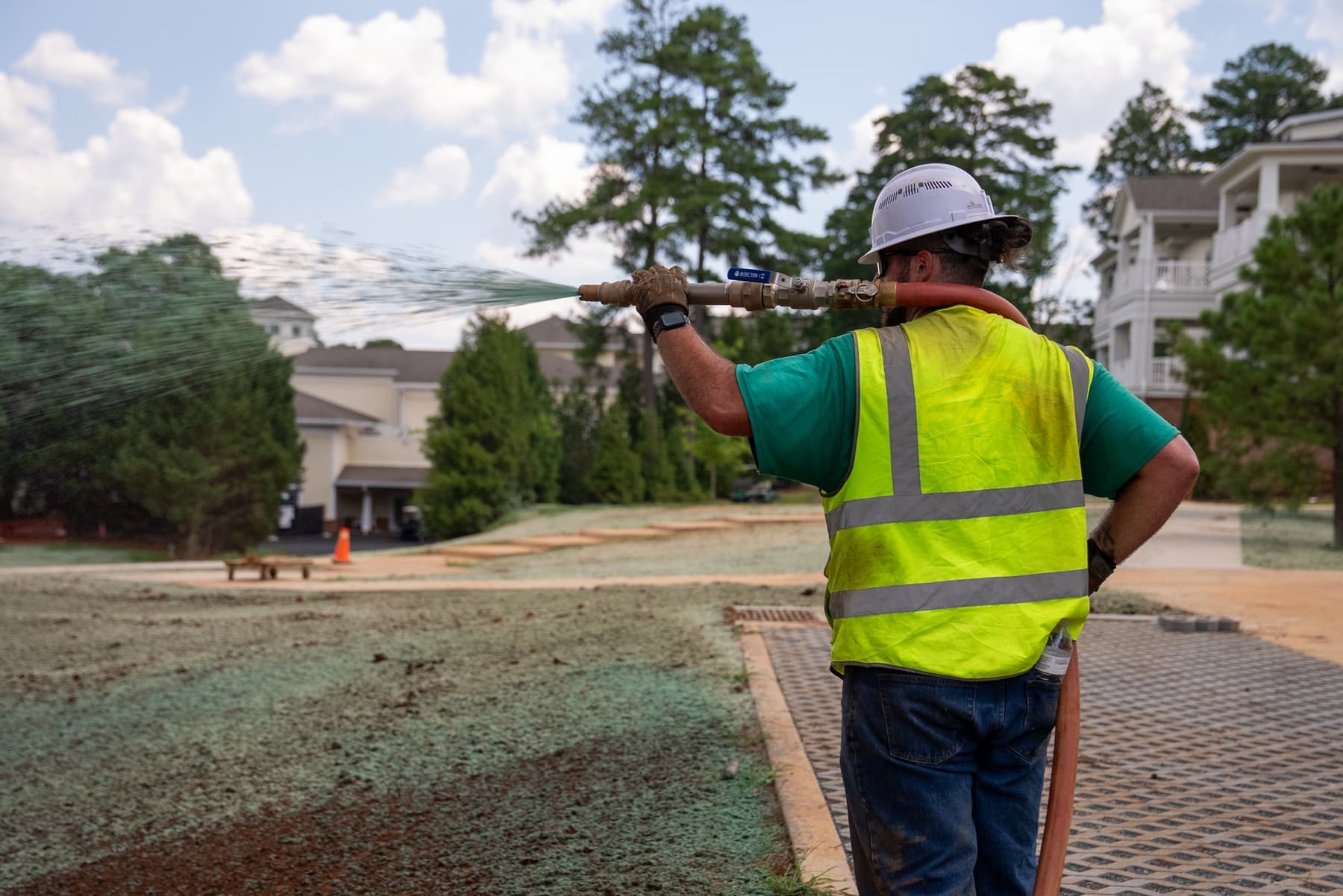 Prime Hydroseeding crew member applying hydroseed slurry at a commercial apartment site