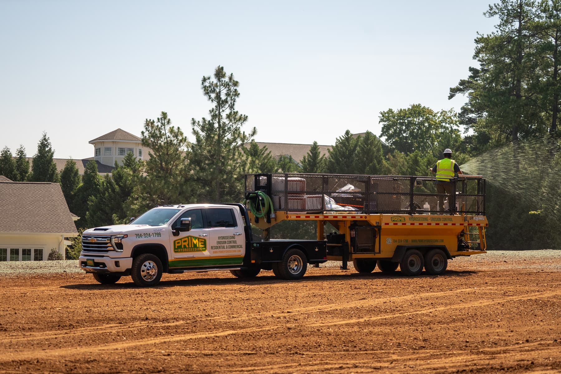 Prime Hydroseeding truck and lift applying hydroseed near a commercial clubhouse