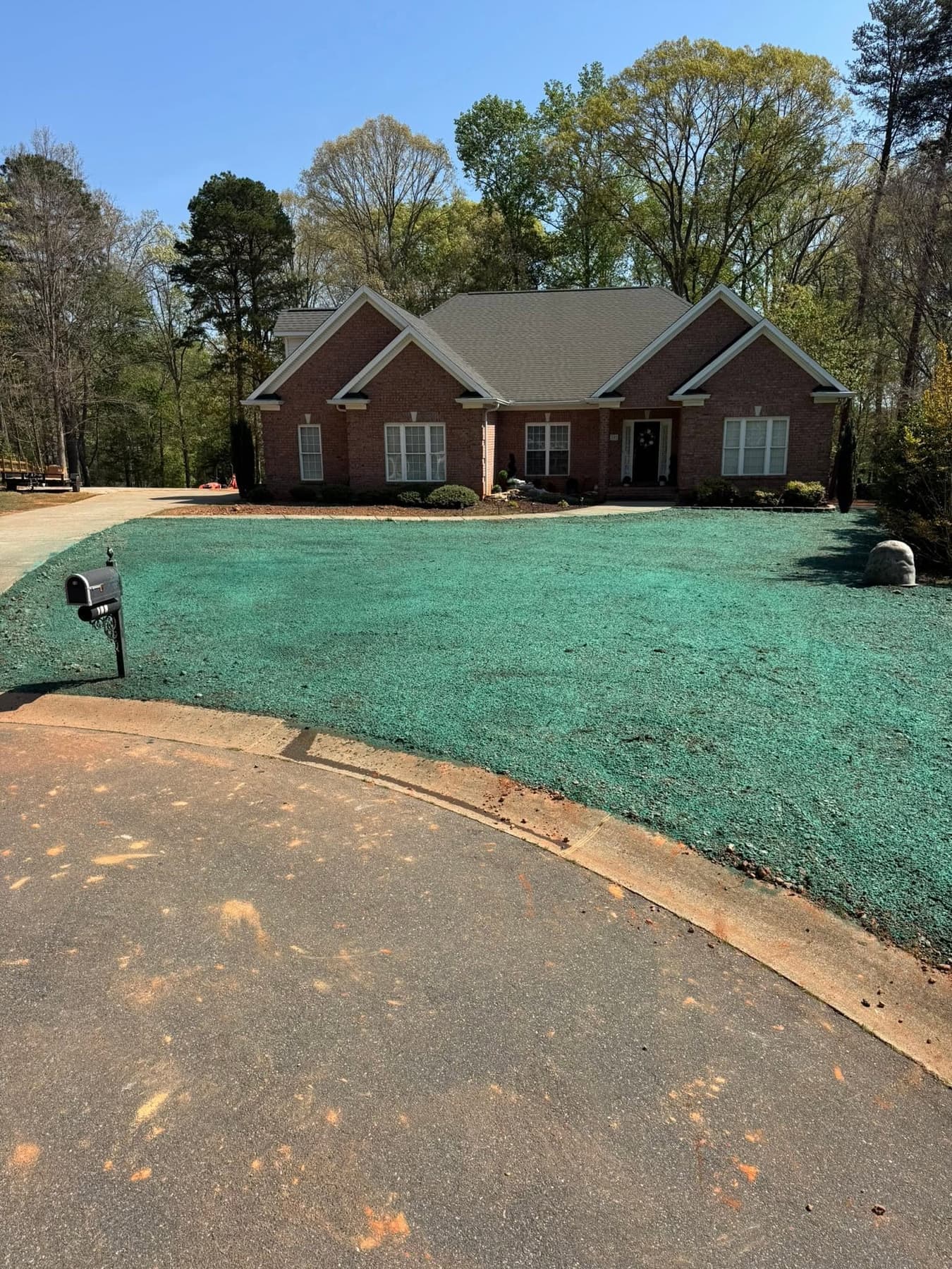 Established green front lawn at a brick residential home with landscaping boulder