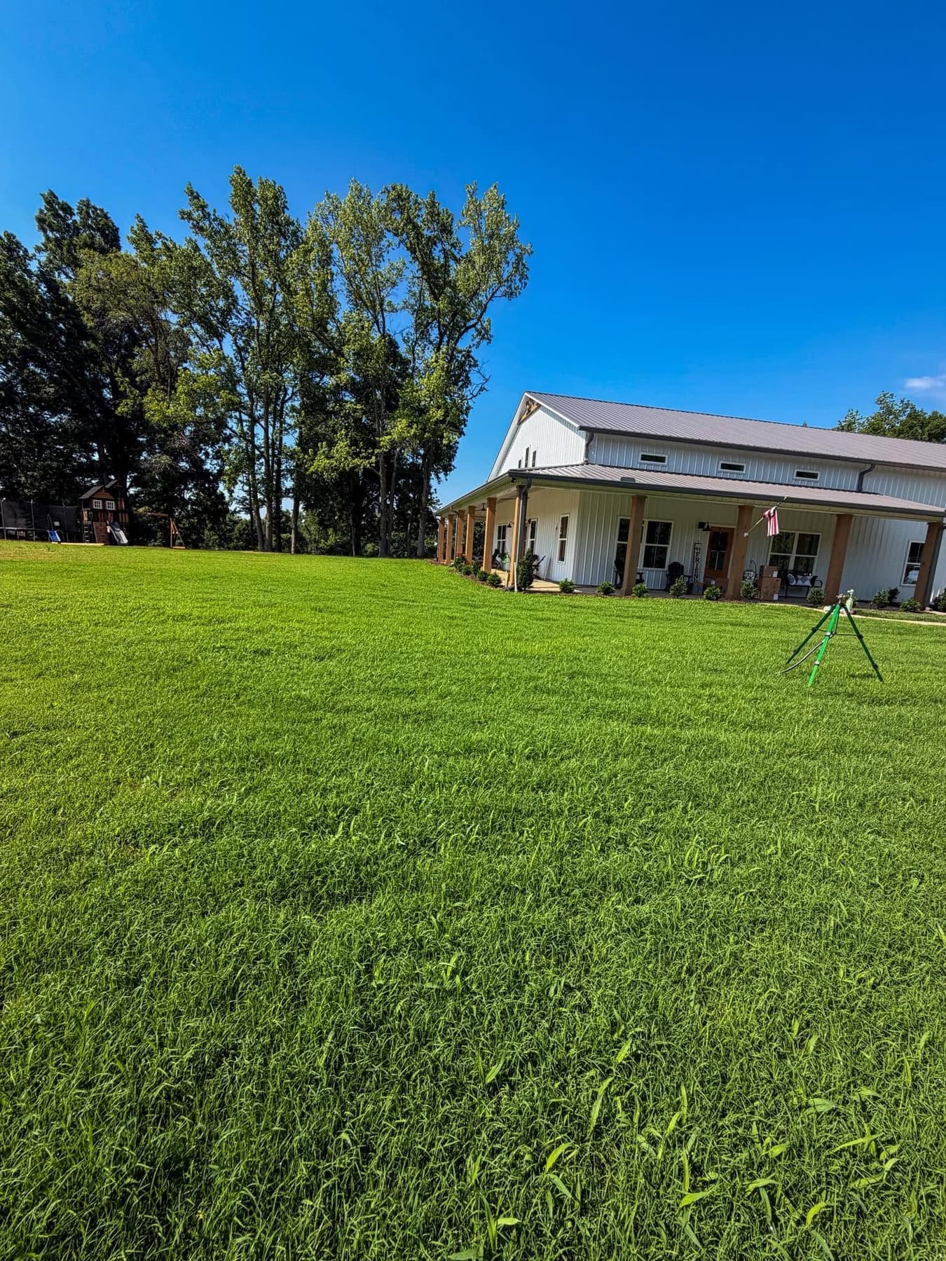 Established green residential lawn in front of a farmhouse-style porch