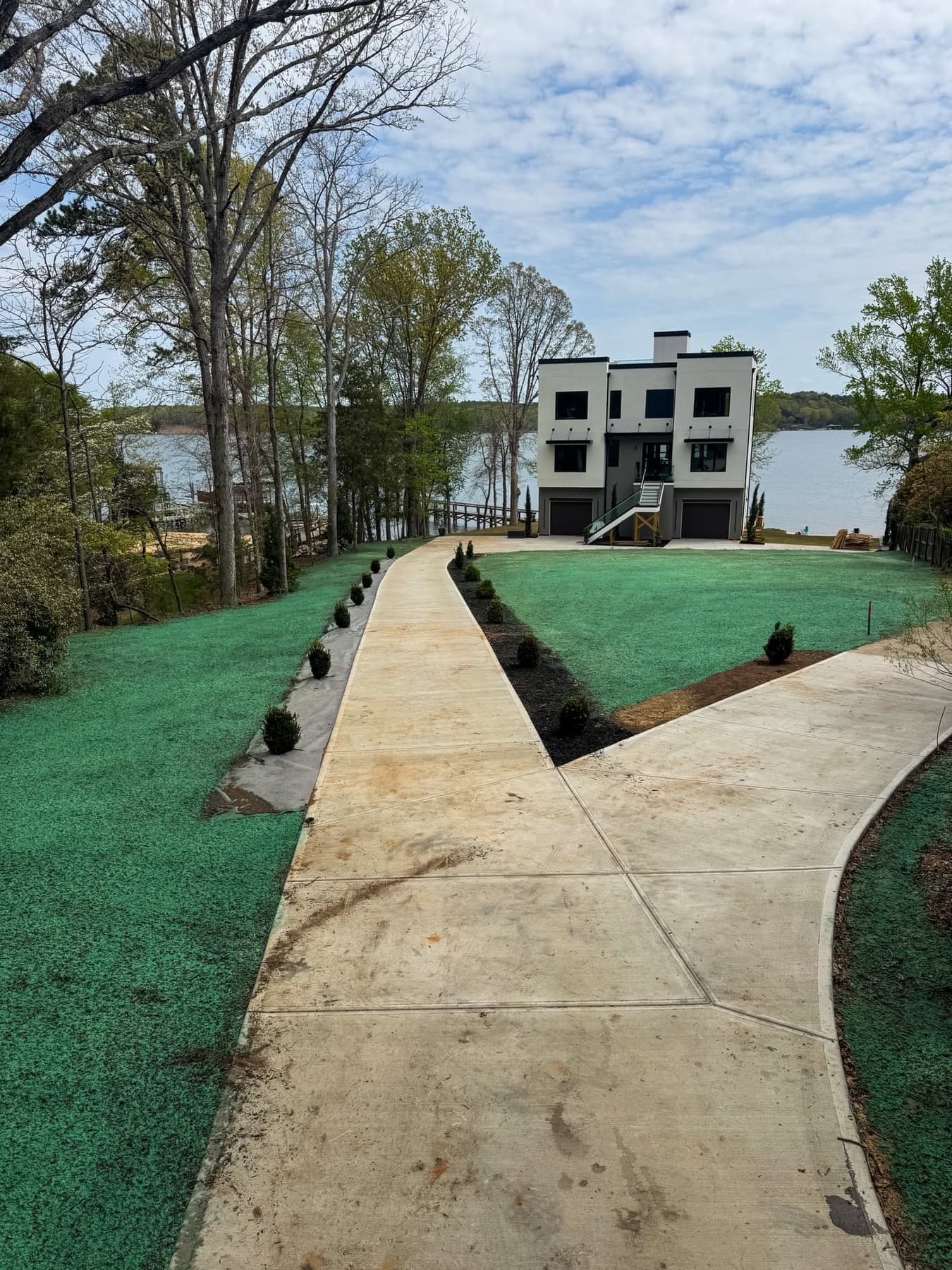 Freshly hydroseeded lawn at a modern lake house with dock and water view