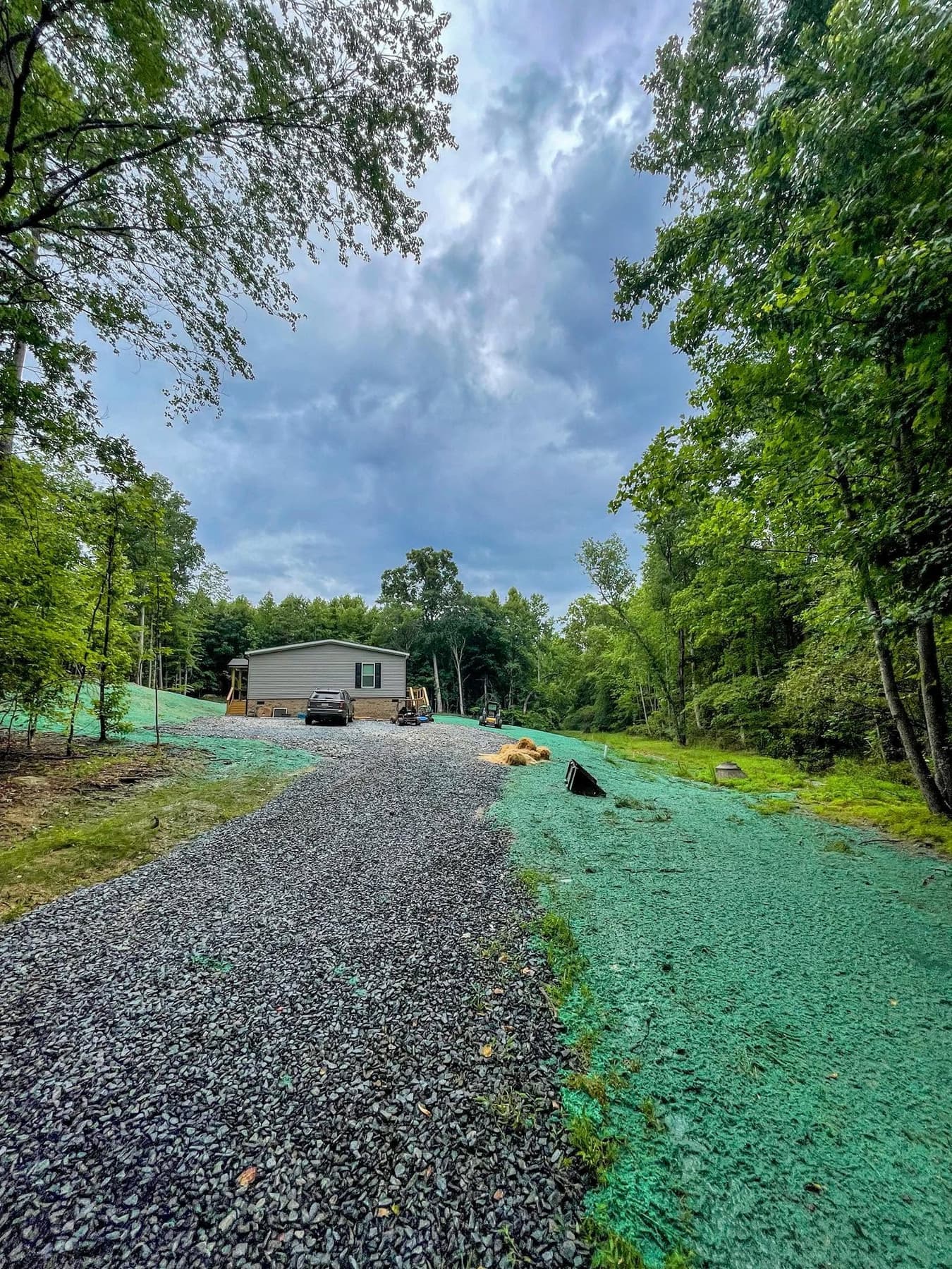 Freshly hydroseeded yard along a gravel driveway at a new residential build