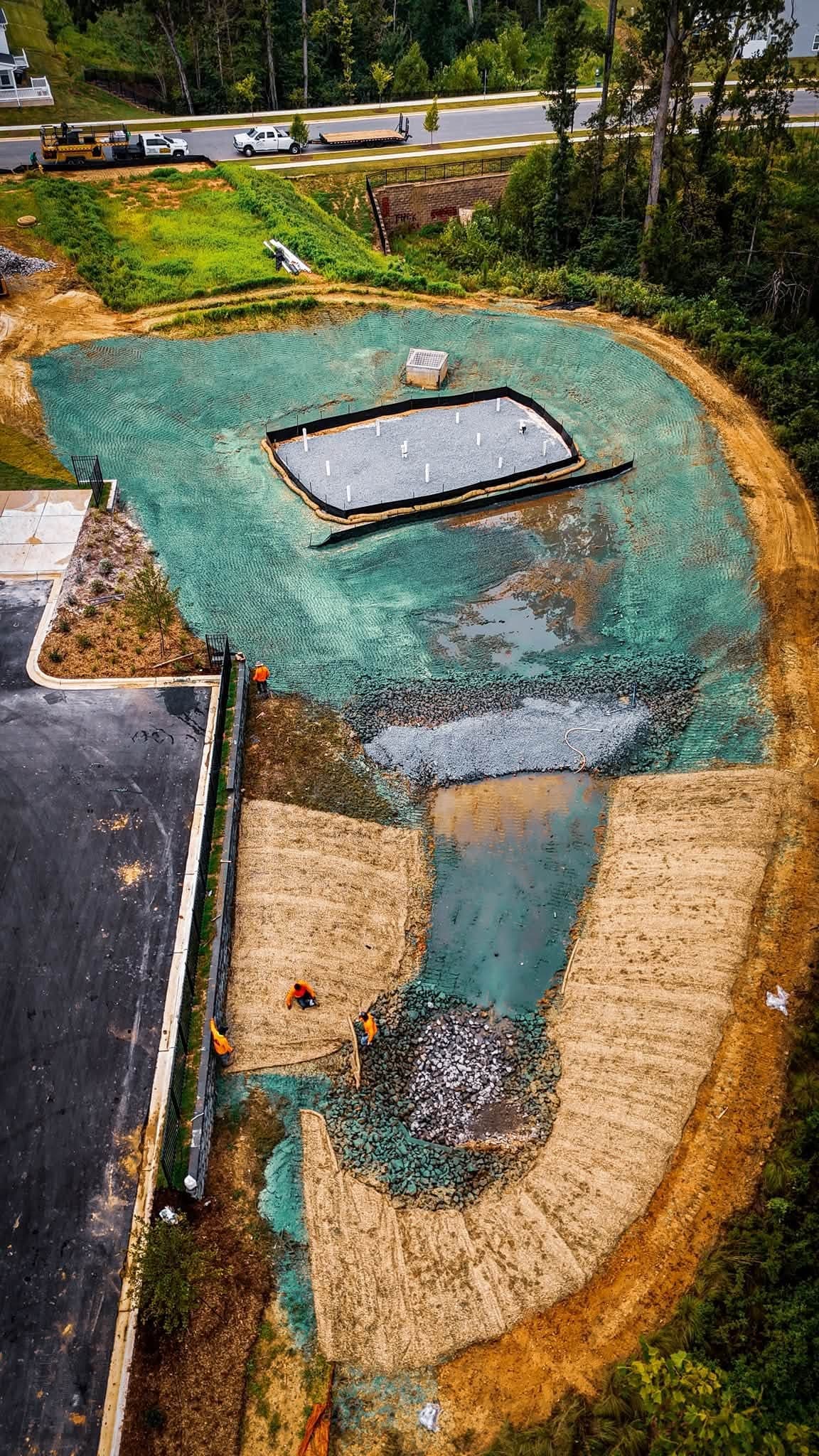 Aerial view of a stabilized stormwater retention pond with erosion control matting