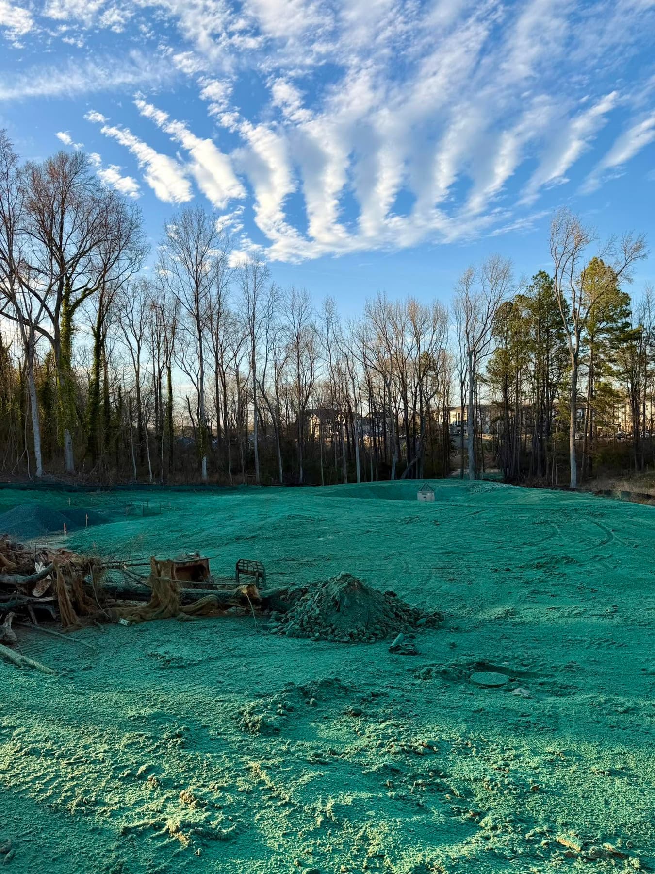 Freshly hydroseeded retention basin construction site with debris pile