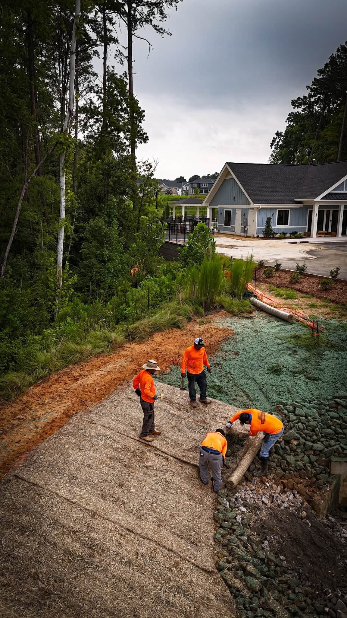 Prime Hydroseeding crew installing erosion control matting on a retention pond slope